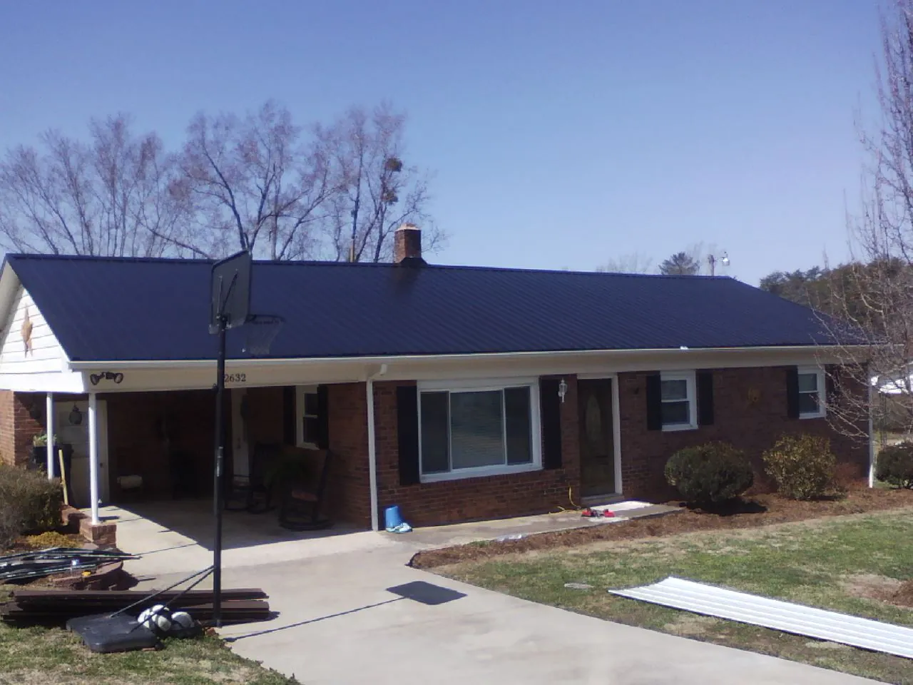 Finished dark blue metal roof on a brick ranch with a carport in Kailua