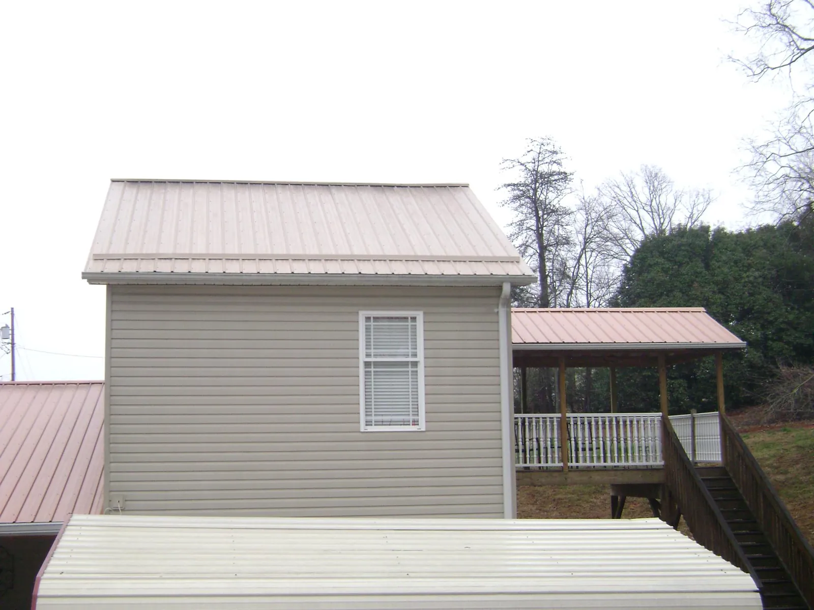 Tan metal roofs on a two story addition and attached porch, from a Roof Replacement job in Kailua